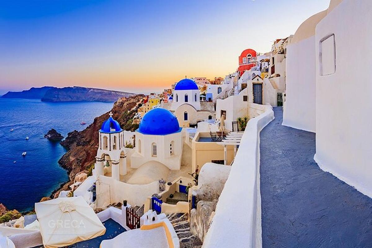 μια ομάδα λευκών κτιρίων με μπλε θόλους και τον ωκεανό