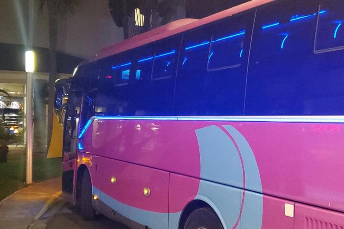 un autobus rosa e bianco parcheggiato in un edificio