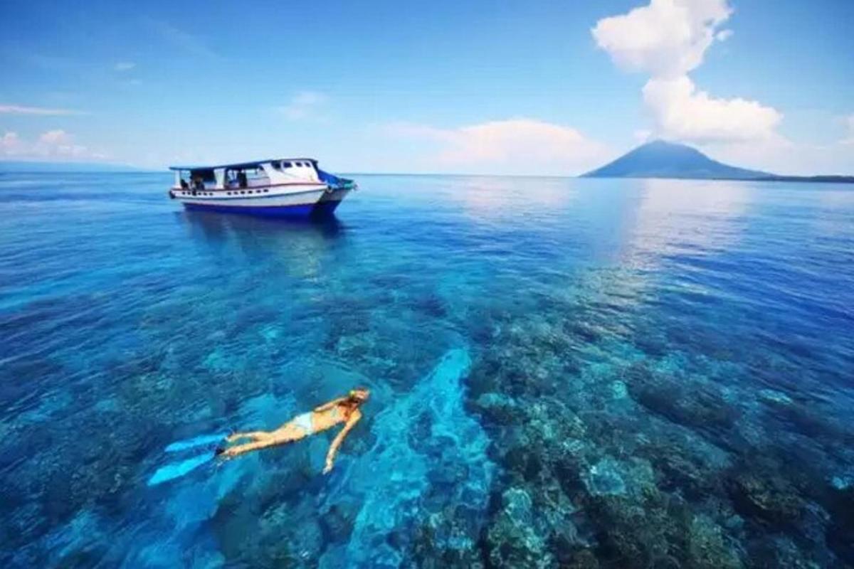 una persona che nuota nell'oceano accanto a una barca