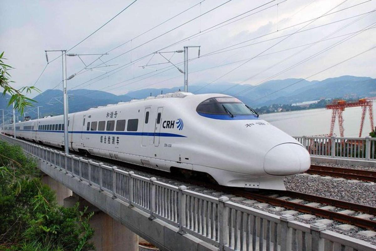 a white train is on the tracks near a bridge
