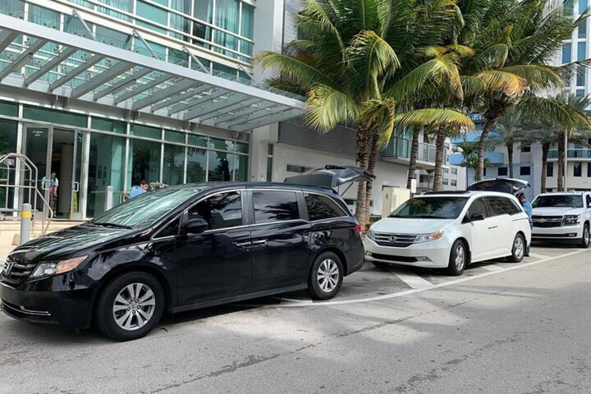dois carros estacionados em frente a um prédio com palmeiras