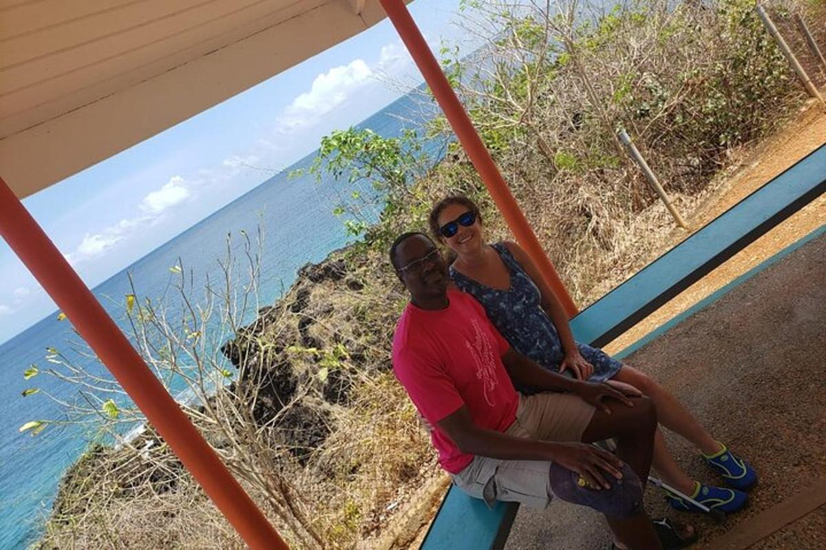 a man and woman sitting on a bench looking at the ocean