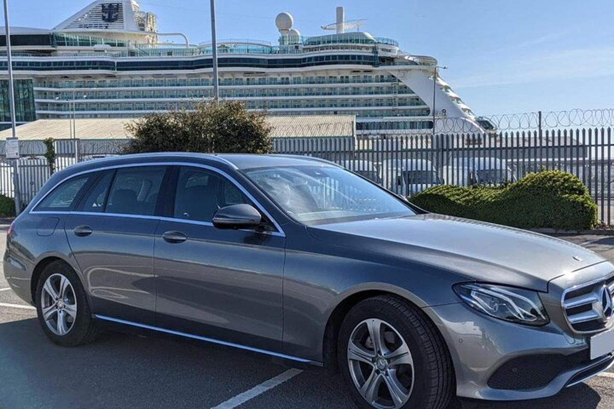 Un coche plateado estacionado en un estacionamiento con un crucero.