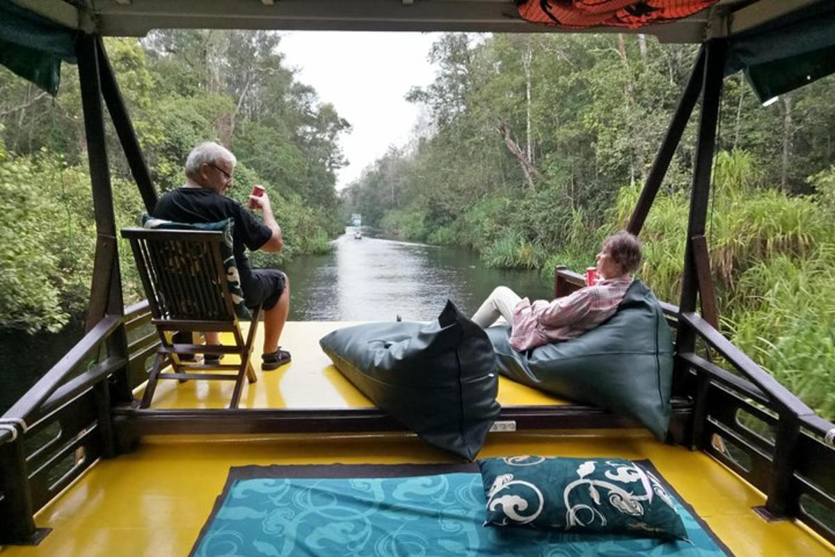 two people sitting on the back of a boat on a river