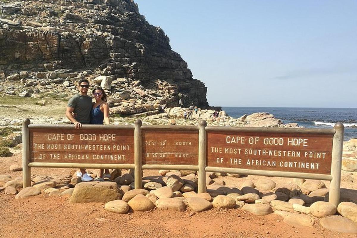 un uomo e una donna seduti su un cartello in spiaggia