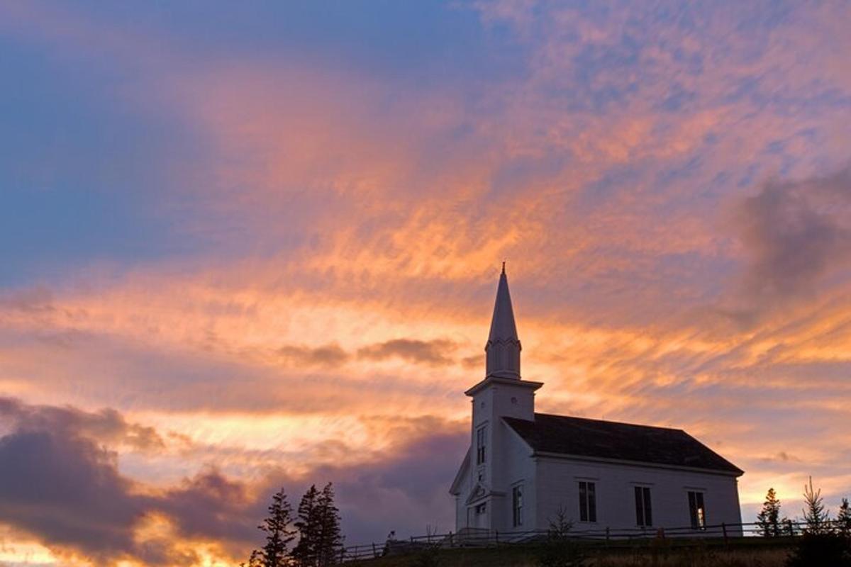 a white church with a steeple and a cloudy sky