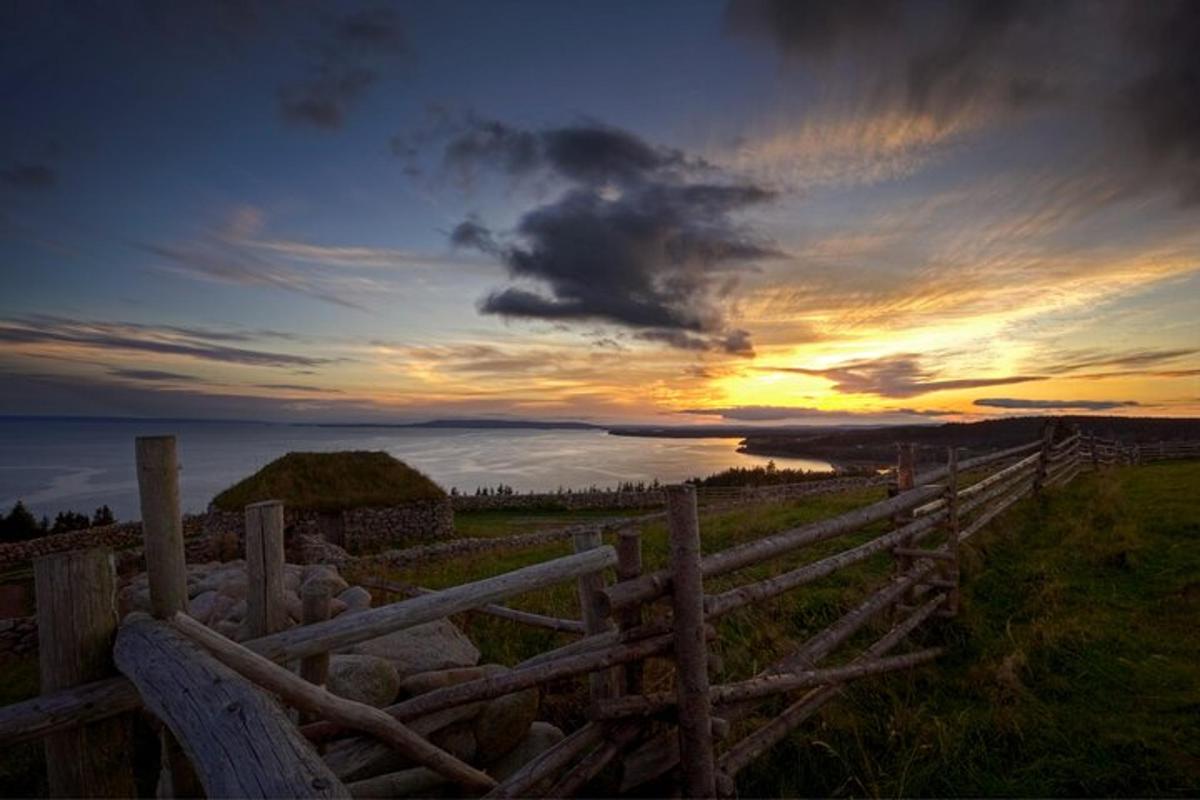 a sunset over the ocean with a wooden fence