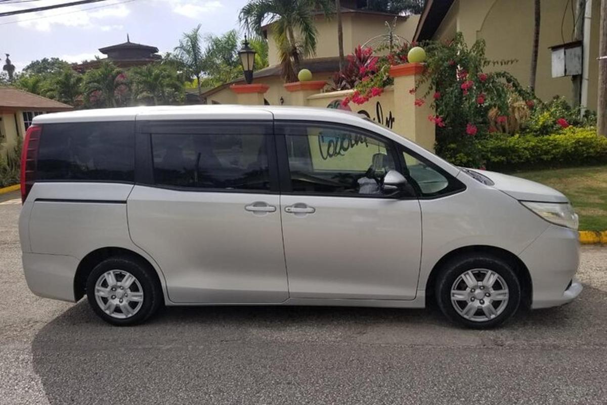 una minivan blanca estacionada frente a una casa