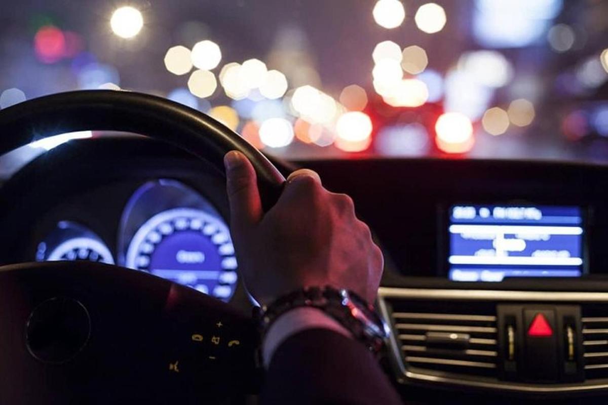 osoba řídící auto s rukou na volantu