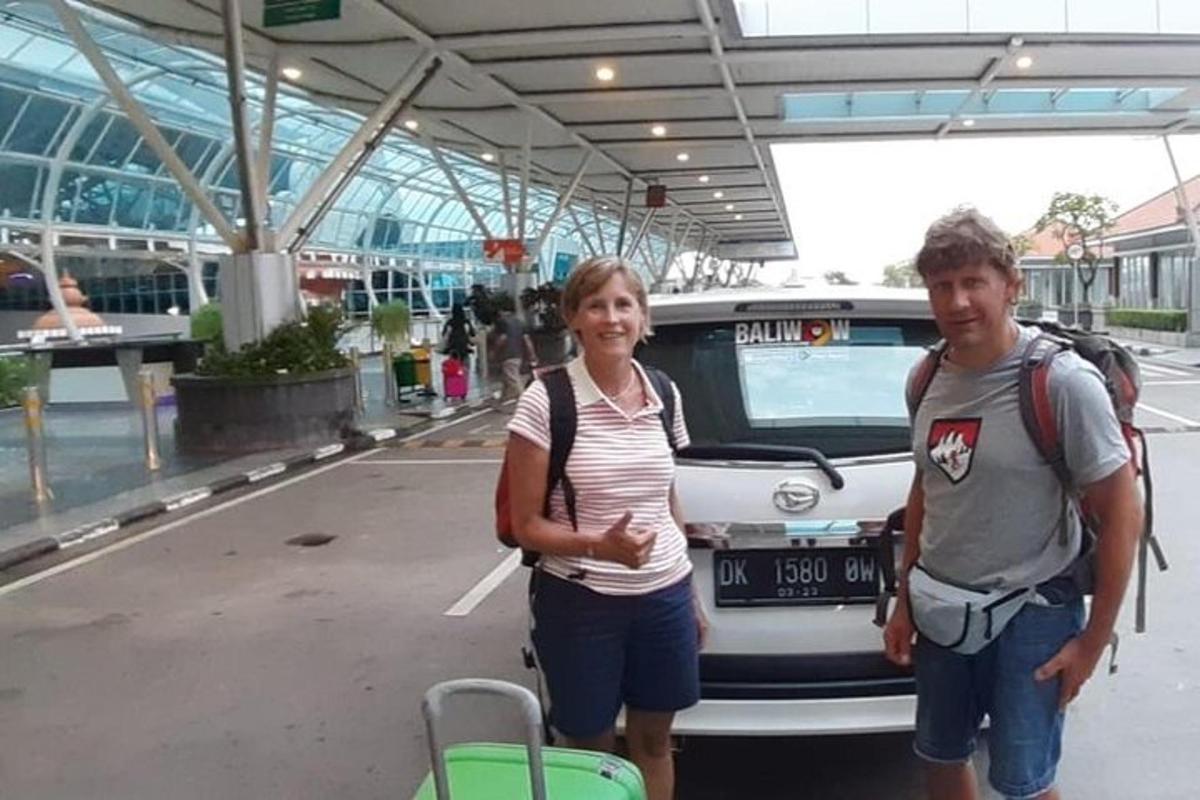 Un hombre y una mujer de pie delante de un coche.
