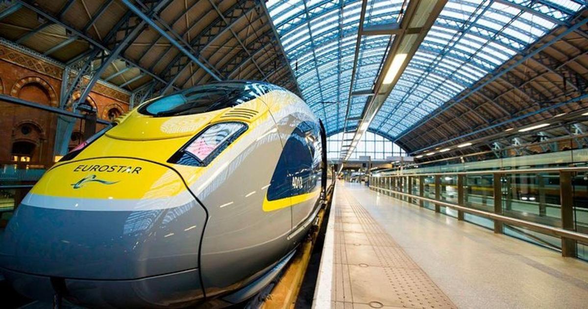Un tren amarillo y blanco en una estación de tren.