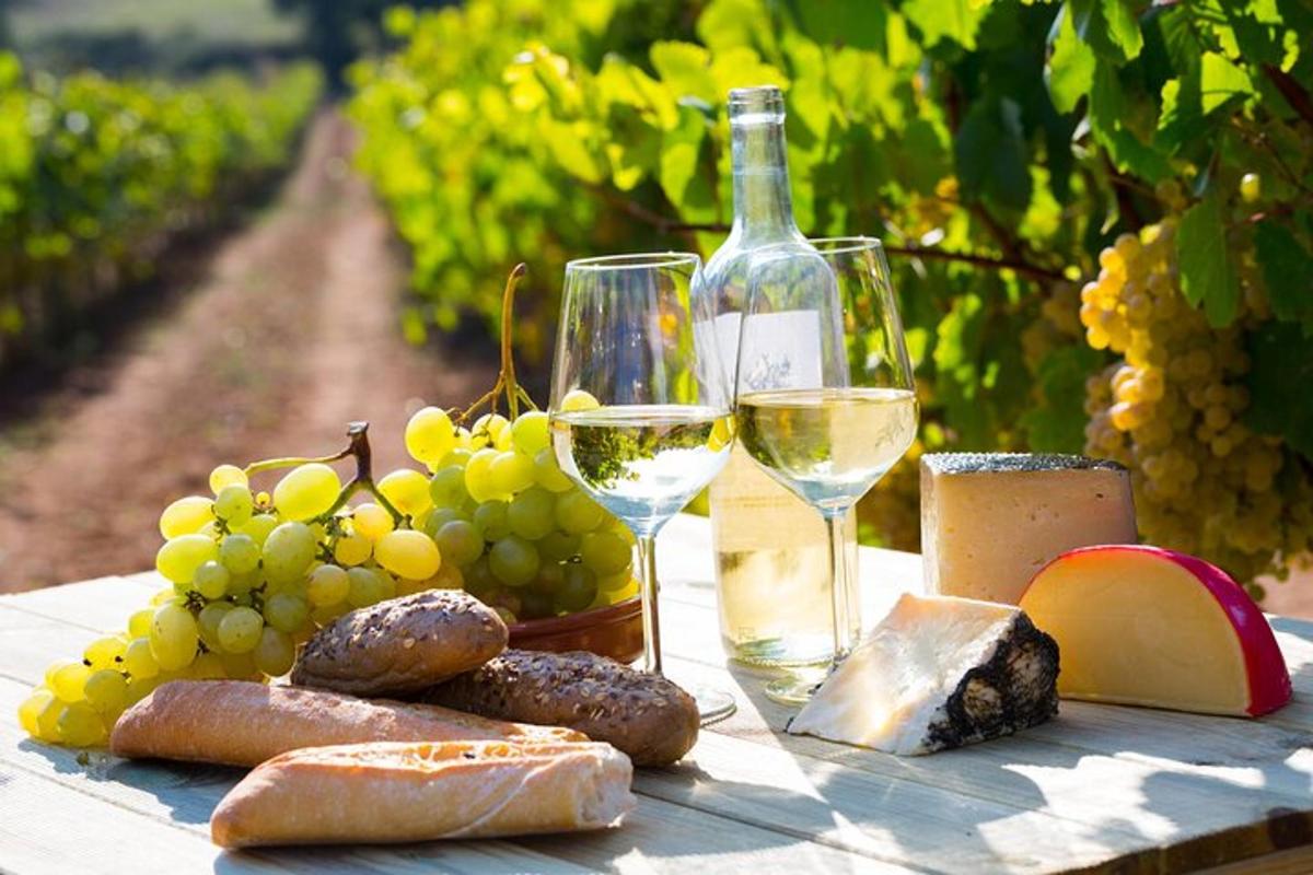 un tavolo con uva, vino, pane e bicchieri da vino