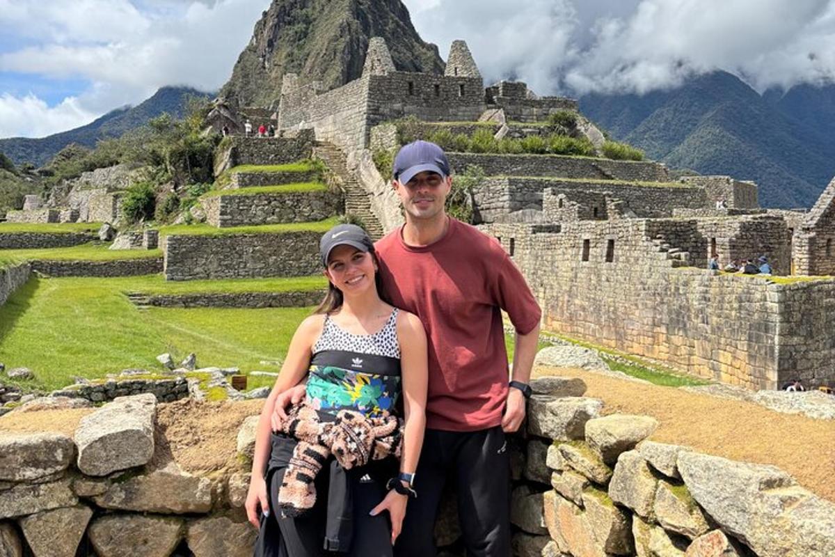 un homme et une femme debout sur un mur avec une montagne