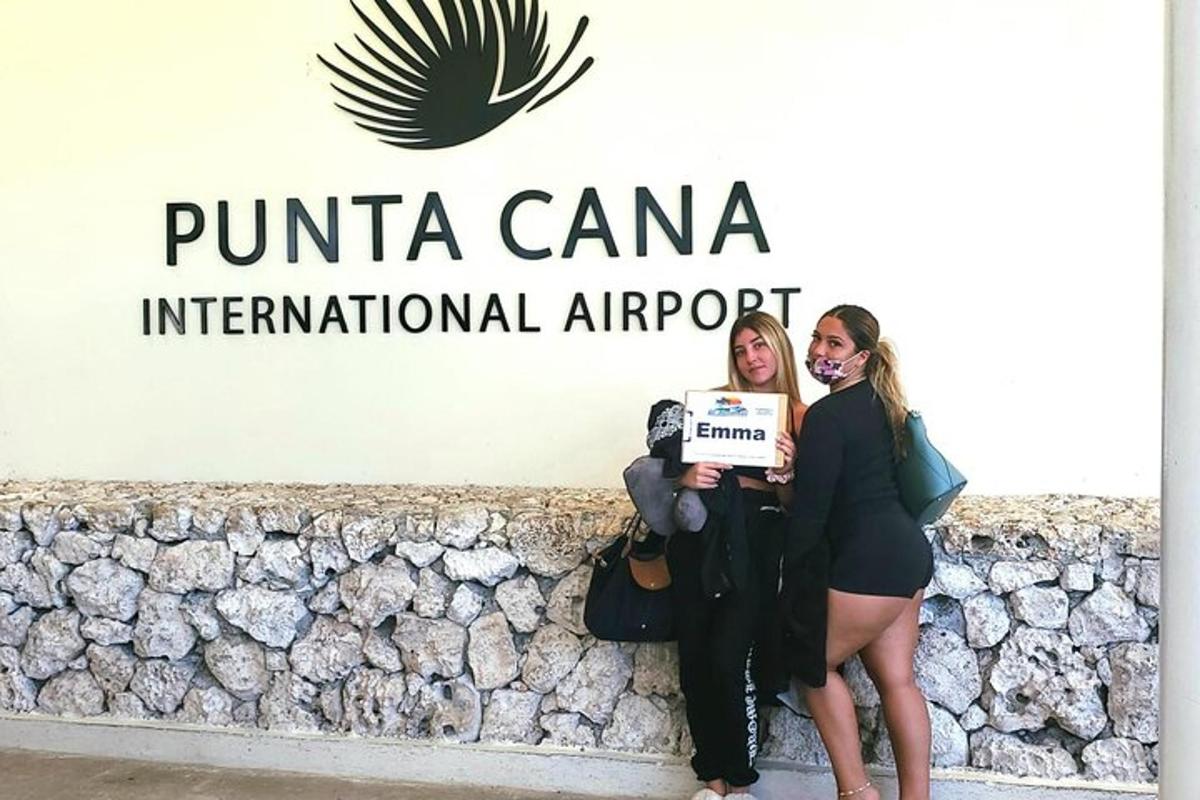two women standing in front of a wall with a sign
