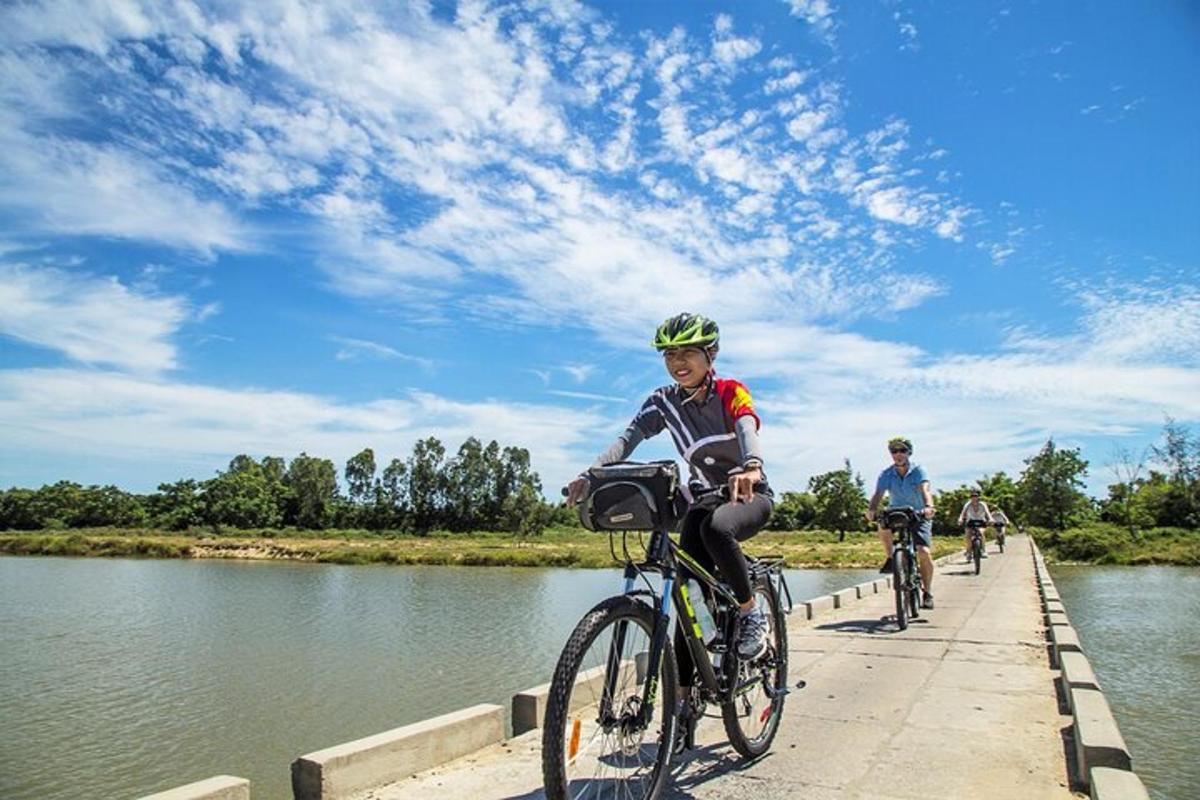 două persoane mergând cu bicicleta pe un pod peste un râu
