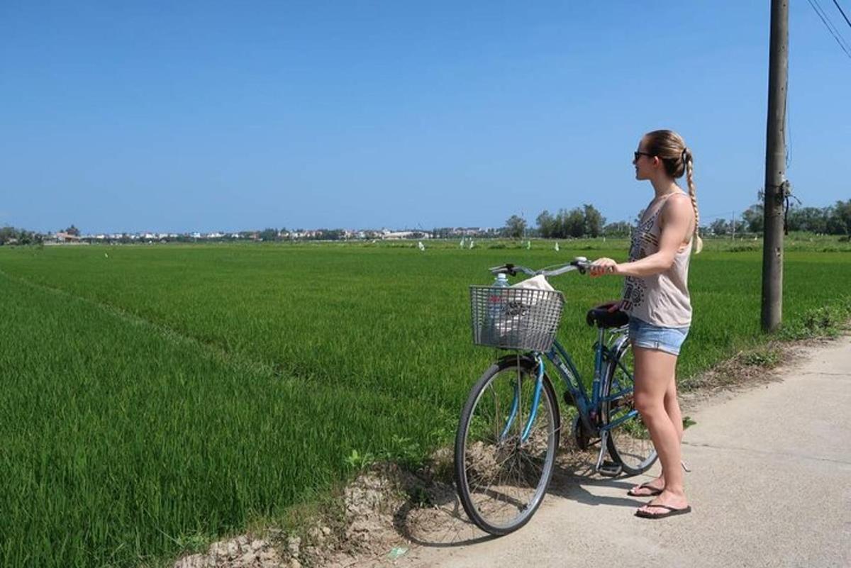 žena stoji pored bicikla na pločniku