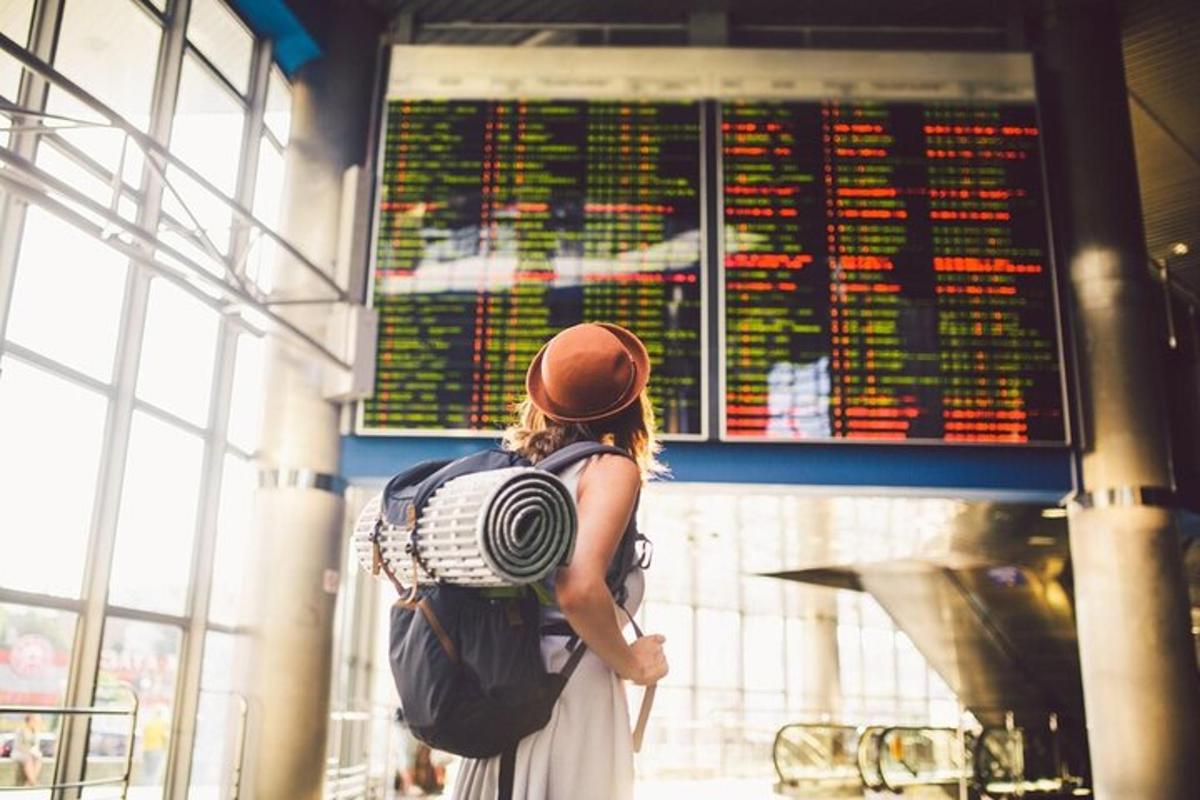 eine Frau mit einem Rucksack schaut auf einen Flugplan