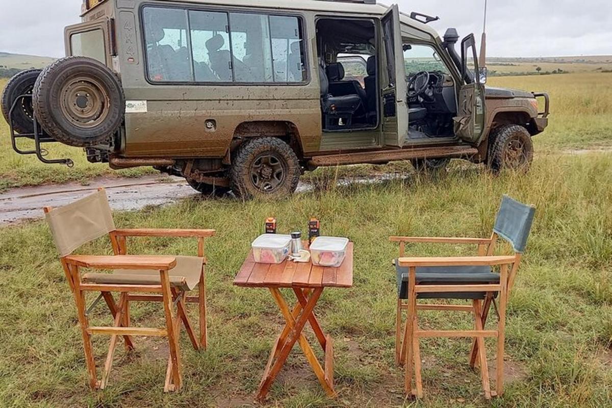 Una mesa y dos sillas y un jeep en un campo.