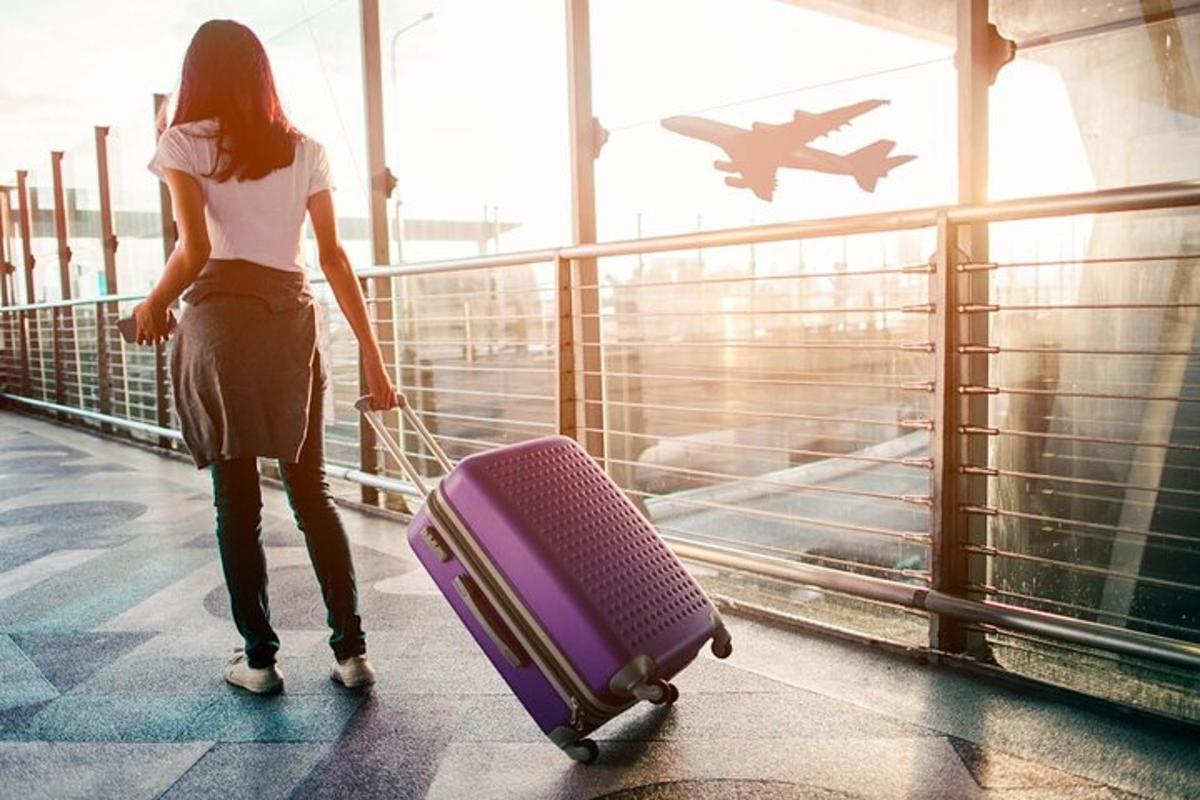 eine Frau, die mit einem Koffer in einem Flughafen geht