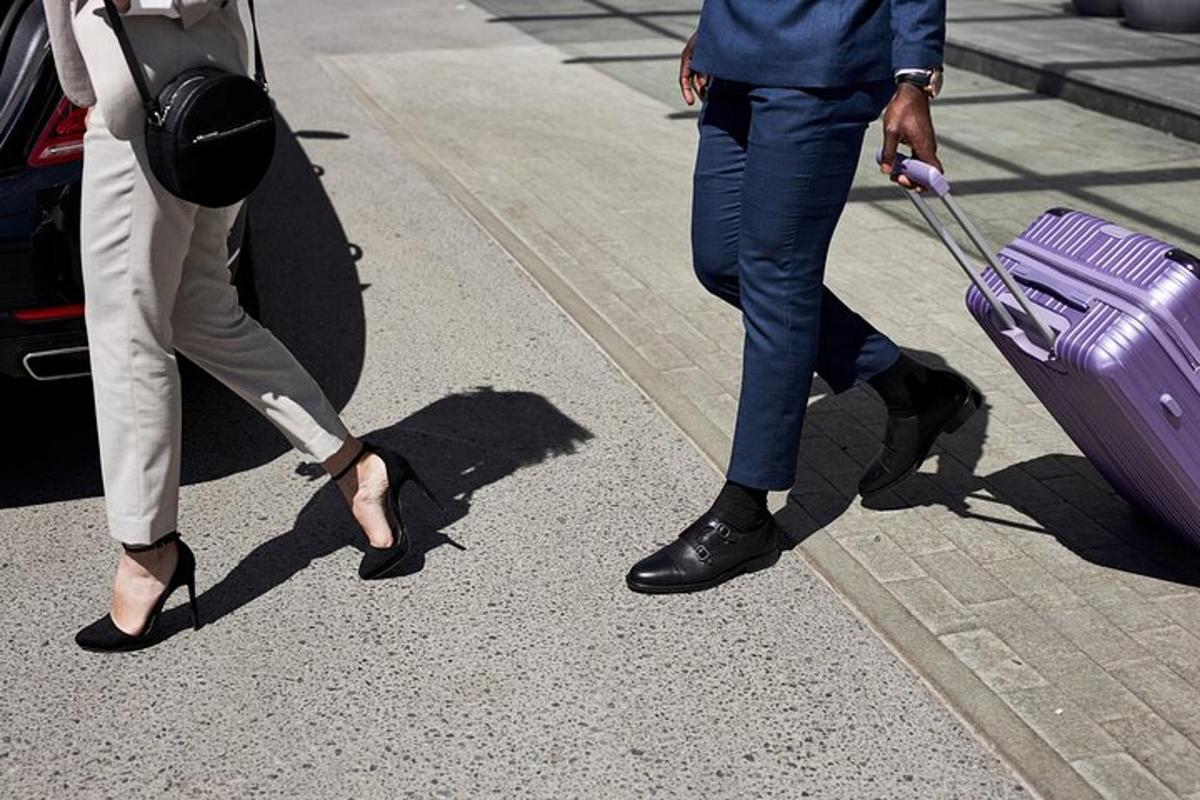 two people walking down the street pulling a purple suitcase