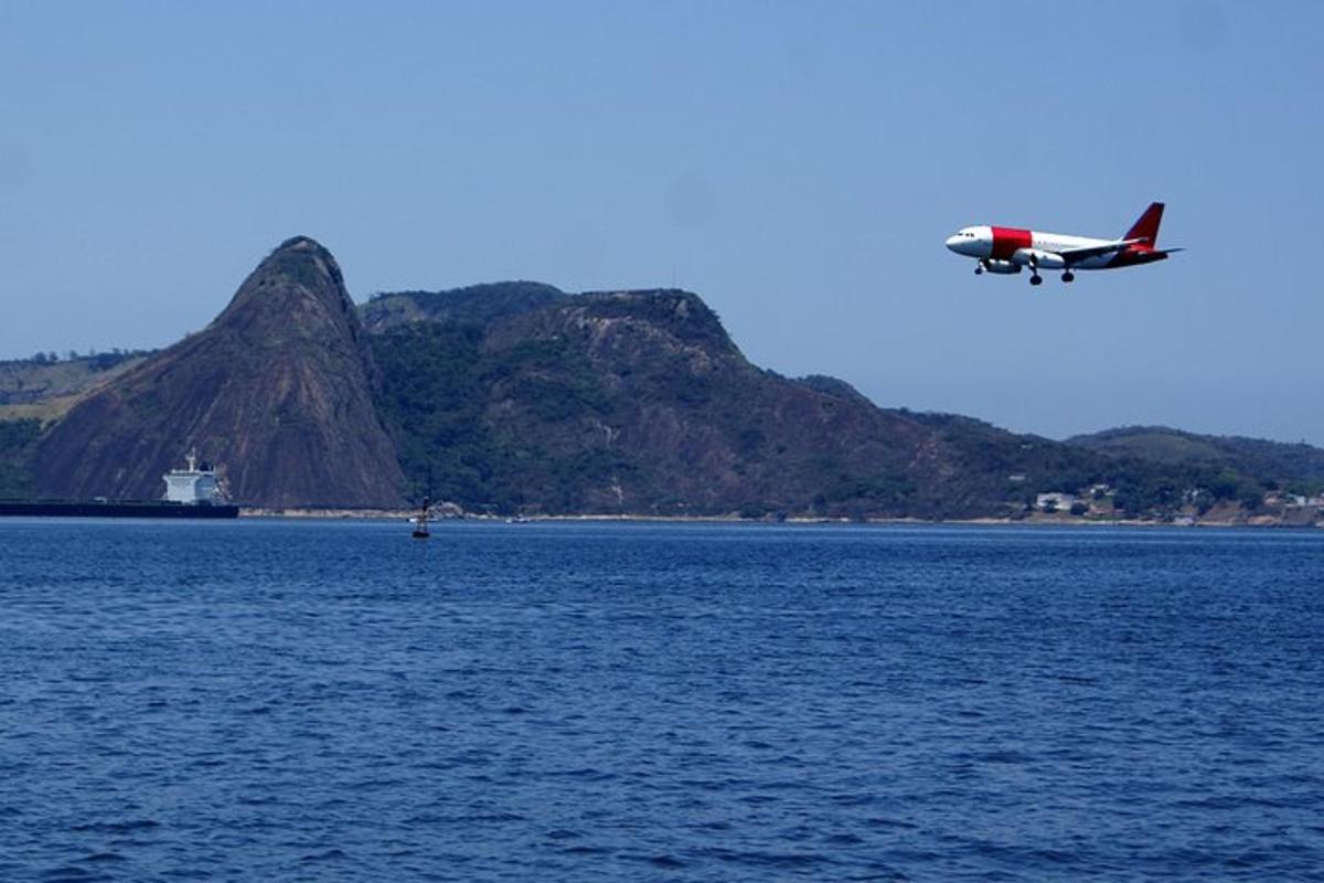 a small plane flying over the water with a mountain