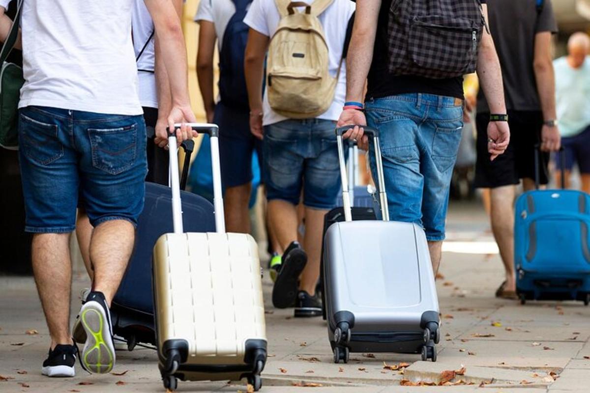 một nhóm người đang đi bộ trên phố với hành lý của họ