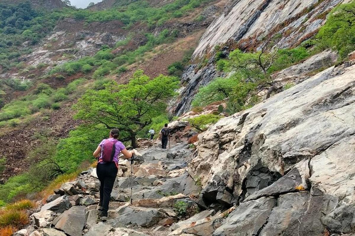 duas pessoas caminhando em uma trilha rochosa na montanha