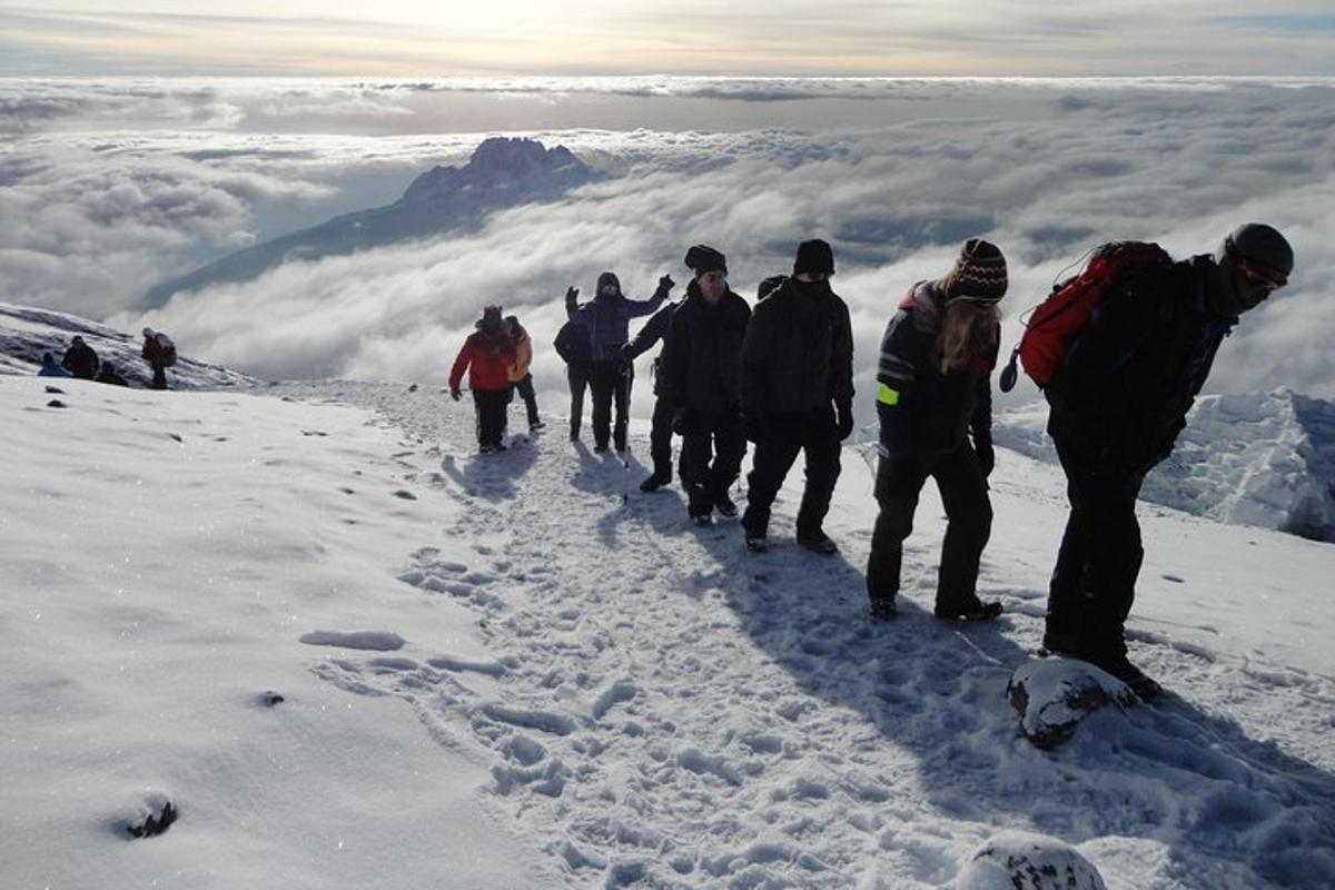 Un grupo de personas de pie en la cima de una montaña cubierta de nieve.