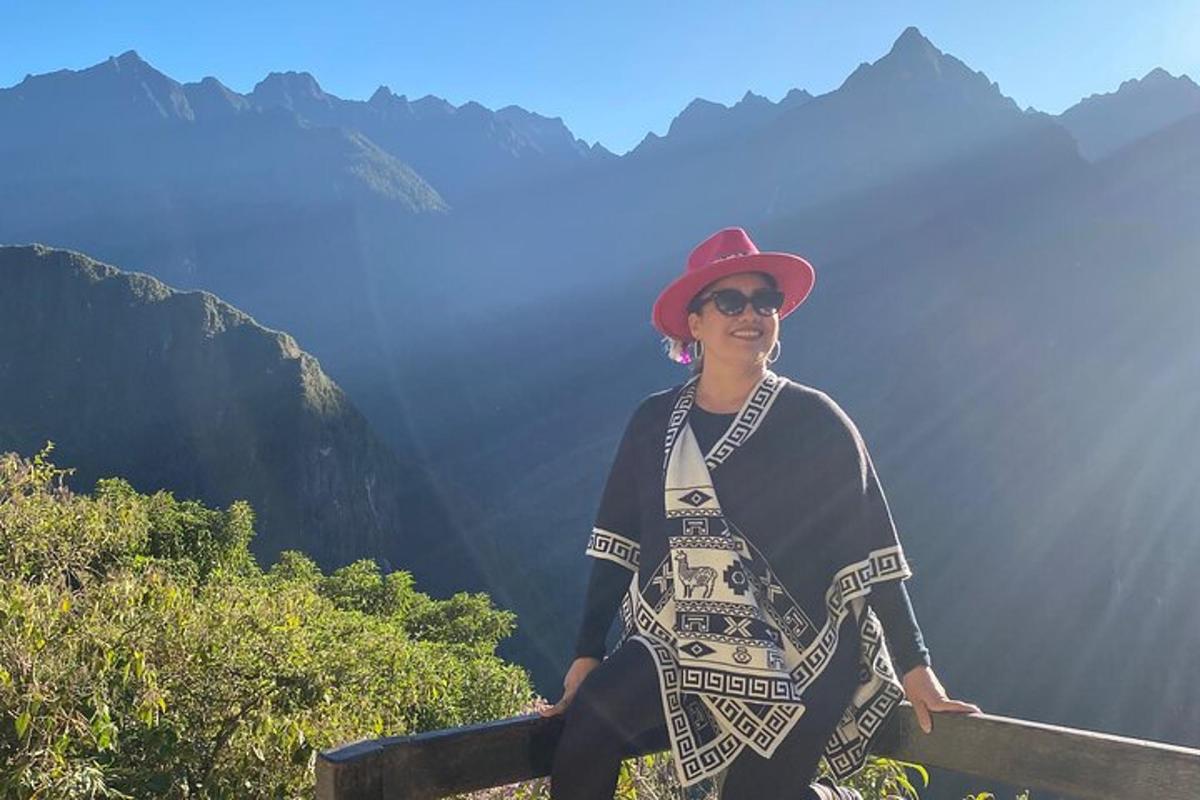 uma mulher sentada em uma cerca em frente às montanhas