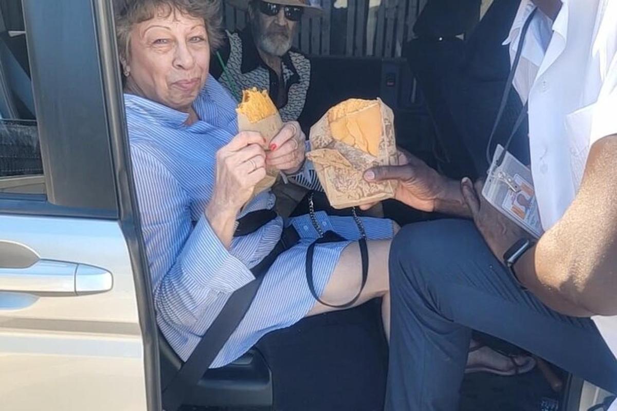 starejša ženska sedi na avtobusu in drži hrano v roki