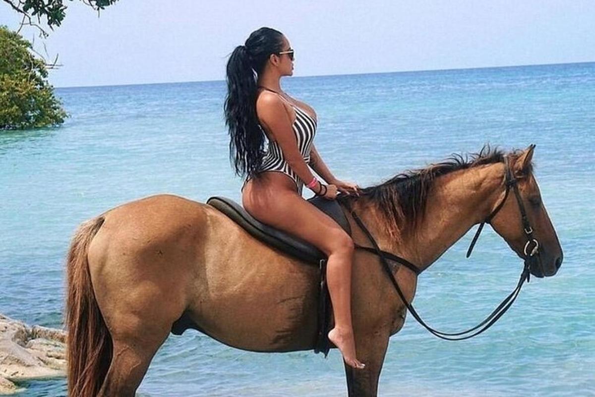жена у бикинију јаше коња на плажи