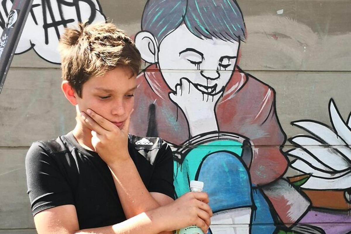 a young boy holding a toothbrush in front of a mural