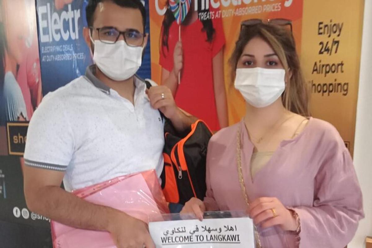 um homem e uma mulher usando máscaras segurando uma placa