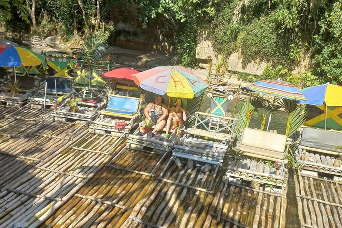 hai người ngồi trên ghế dưới ô dù trên bãi biển