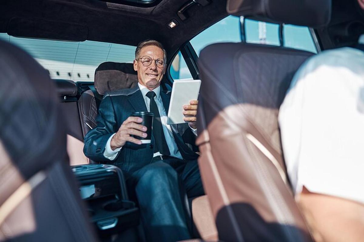 um homem sentado no banco de trás de um carro com um tablet