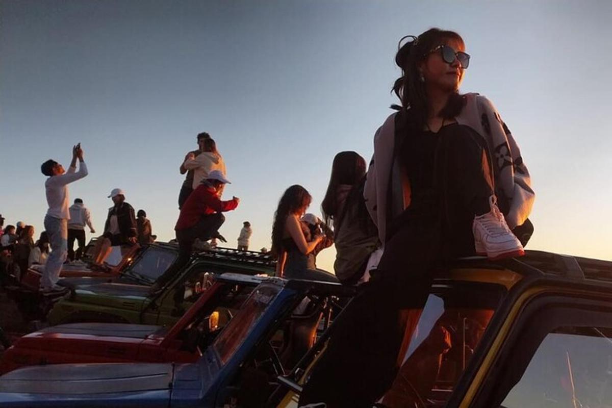 Un grupo de personas paradas encima de los coches.