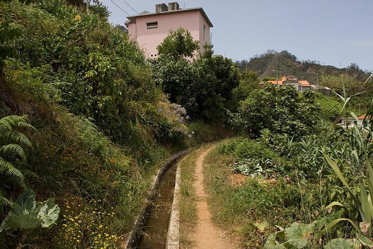 uma estrada de terra que leva a uma casa rosa em uma colina