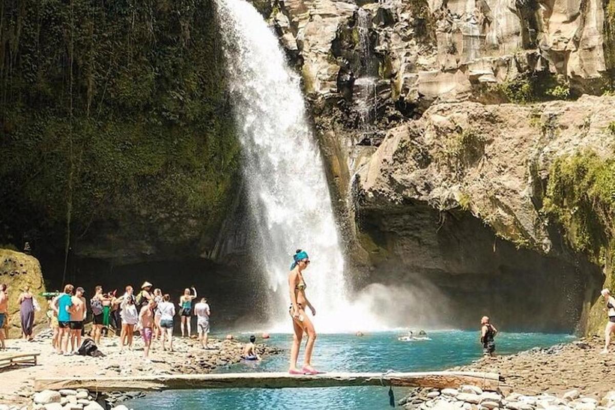 un grup de persones a la platja a prop d'una cascada