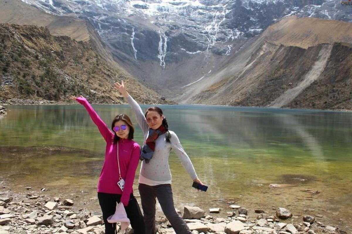 Dos mujeres de pie frente a un lago de montaña