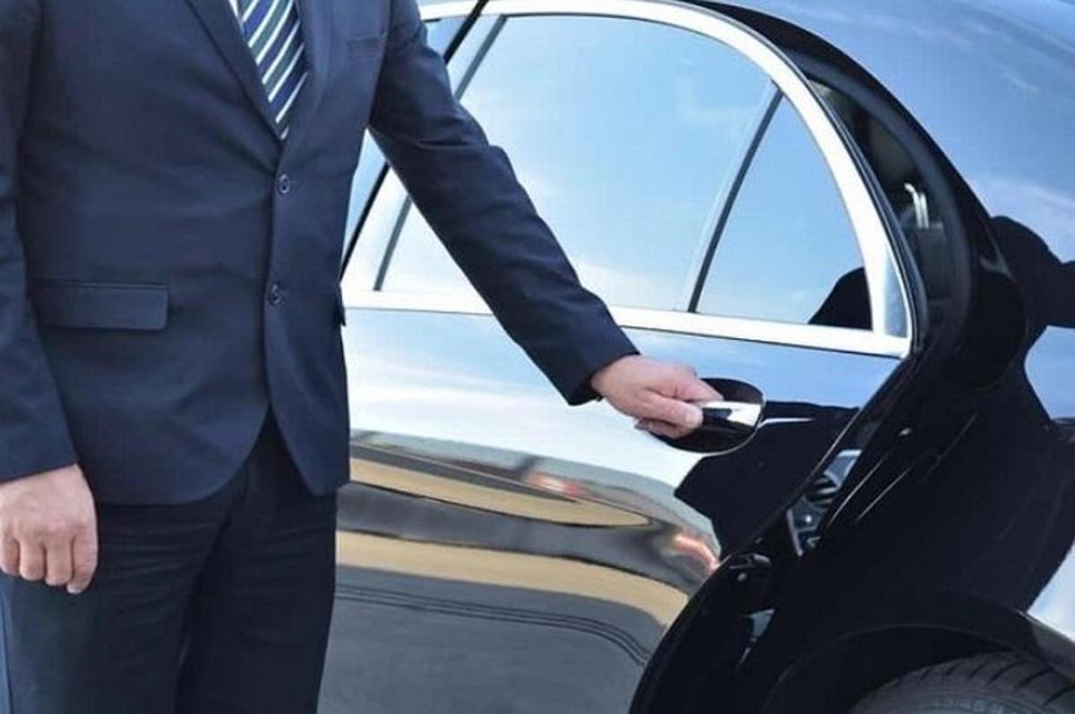 ülikonnas mees auto ust avamas