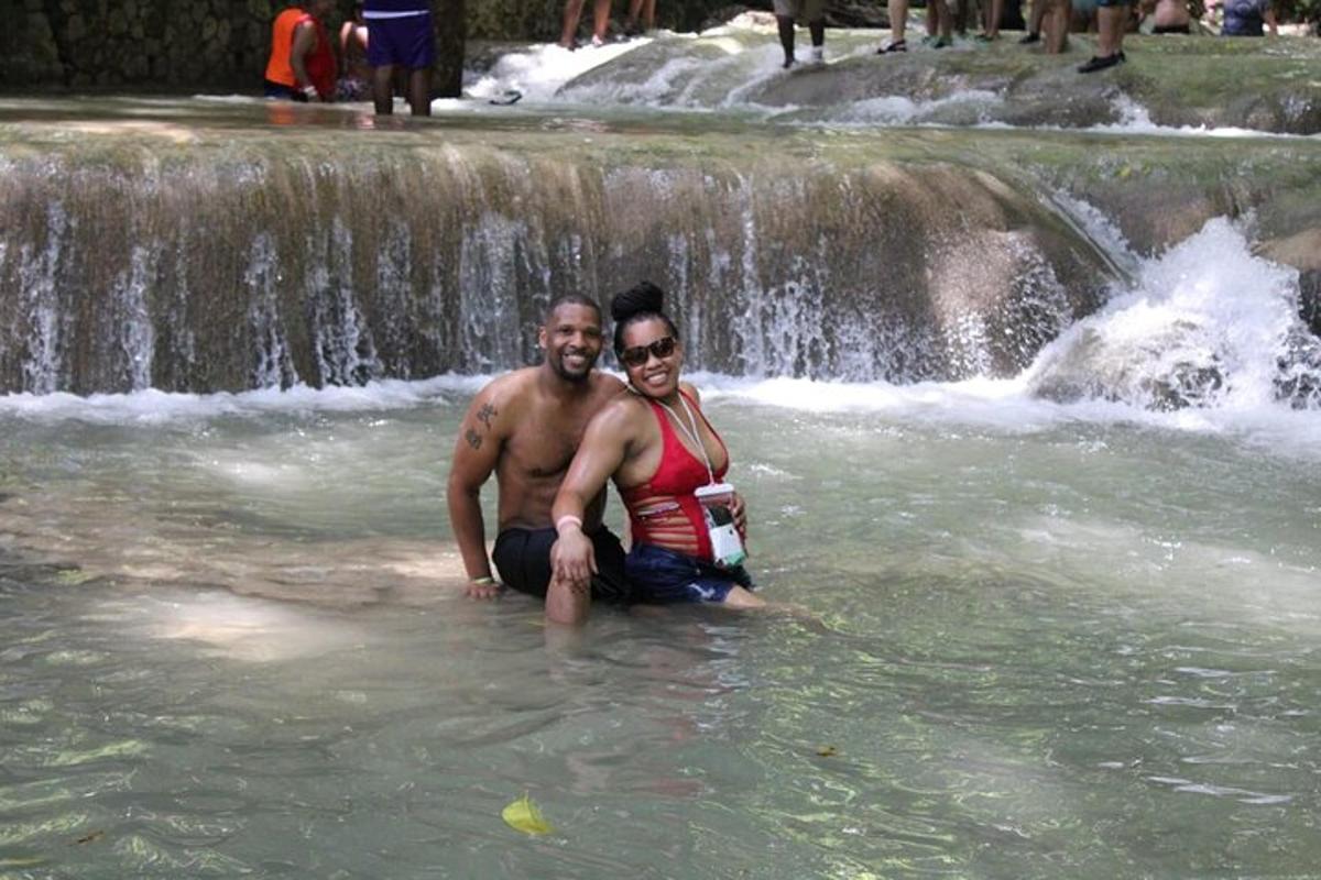 dues persones assegudes a l'aigua davant d'una cascada