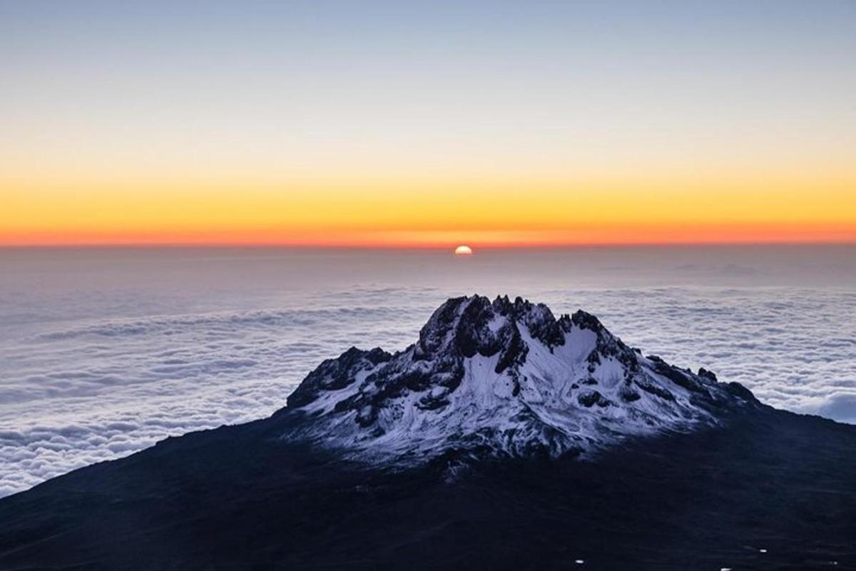 uma montanha nas nuvens com o pôr do sol ao fundo
