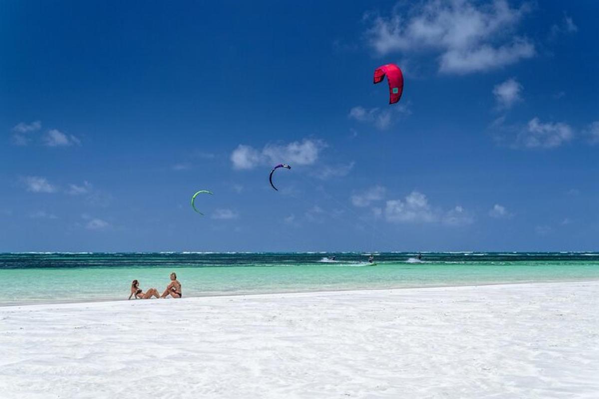duas pessoas estão empinando pipas em uma praia