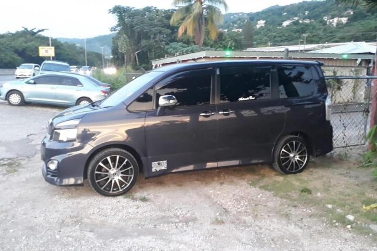 sebuah mobil van hitam diparkir di samping pagar