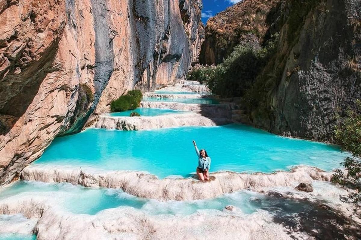 a person sitting on a rock in a pool of blue water