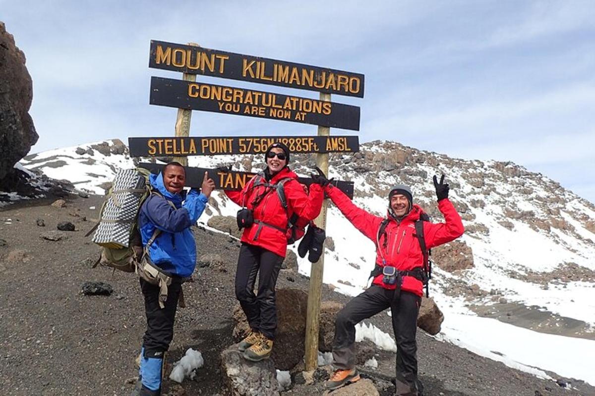 tre persone in piedi accanto a un cartello su una montagna