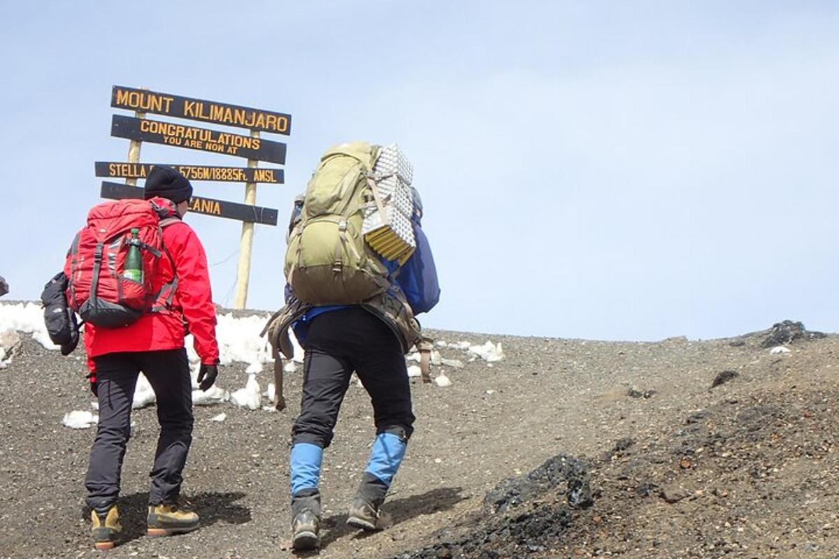 due persone con zaini che salgono su una montagna con un cartello