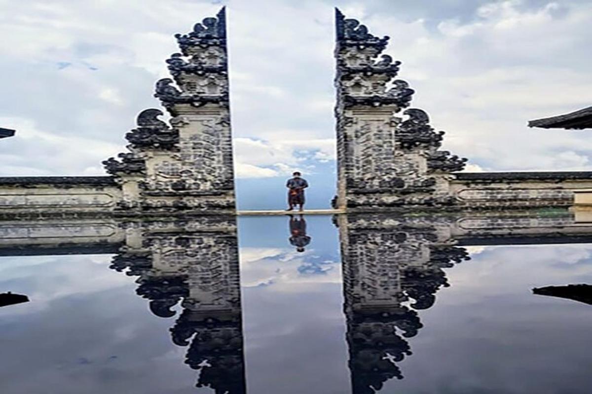a man standing on a bridge with its reflection in the water