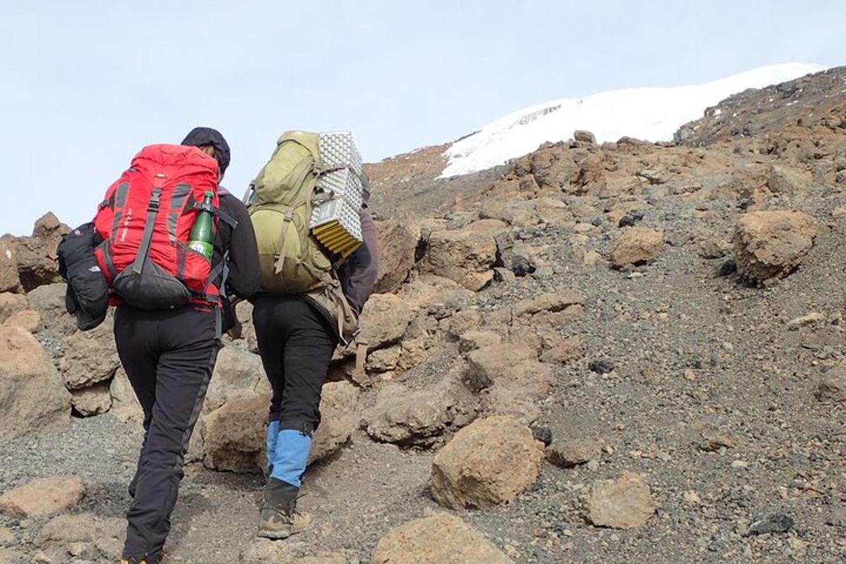 due persone con zaini che camminano su una montagna rocciosa