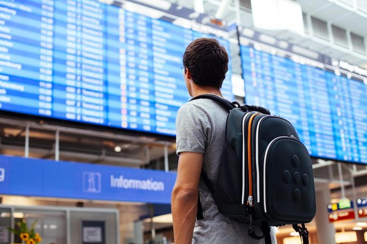 a man with a backpack standing in front of an airport
